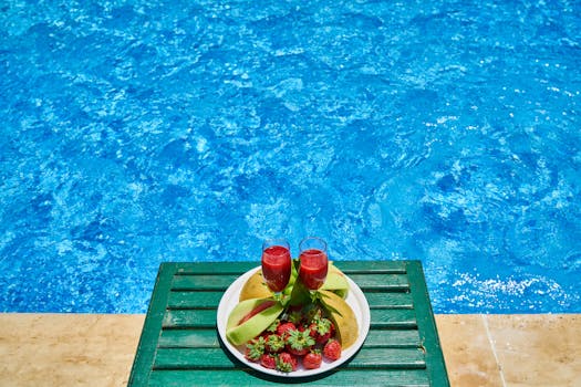 Two refreshing fruit drinks with strawberries by a pool, offering a vibrant summer vibe.