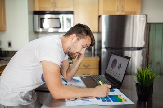 A man reviewing financial charts on a laptop at home, emphasizing data analysis.