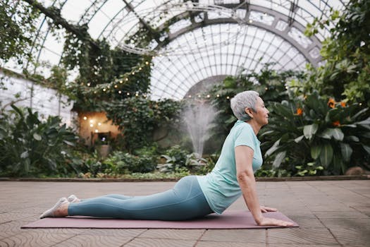 Elderly woman performing yoga cobra pose in a lush botanical greenhouse setting.