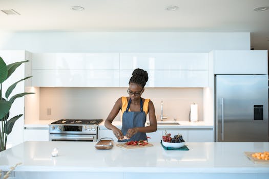 A woman chops strawberries in a sleek kitchen, creating a fresh meal.