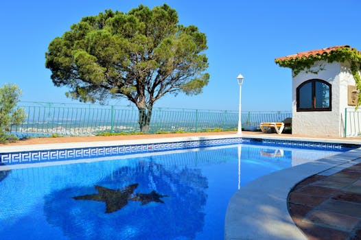 A tranquil poolside scene under a bright blue sky, perfect for relaxation and leisure.