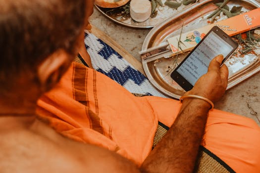 A person in traditional attire reads a script on a smartphone during a cultural ceremony.