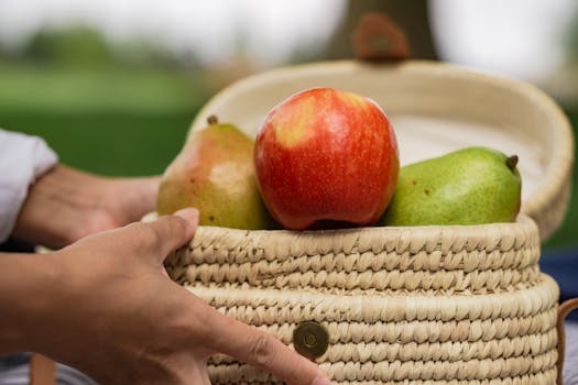 Close-up of apples and pears in a woven basket outdoors, symbolizing health and freshness.