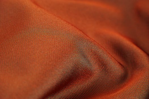 Close-up of a soft, smooth orange fabric texture, capturing its silky sheen.