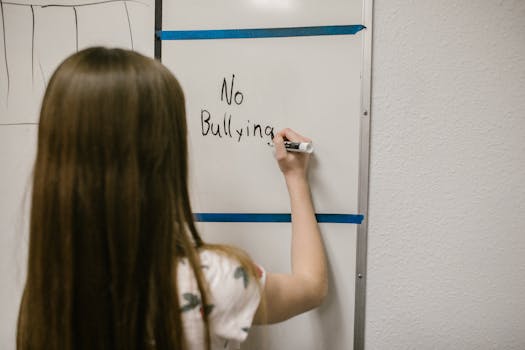A young girl writes 'No Bullying' on a whiteboard, promoting anti-bullying awareness.