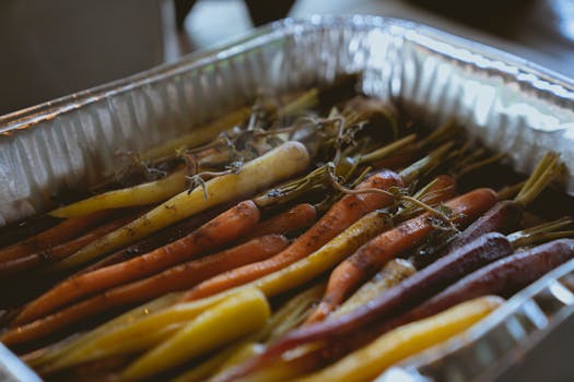 Close-up of grilled rainbow carrots in an aluminium tray, showcasing vibrant and healthy roasted vegetable options.