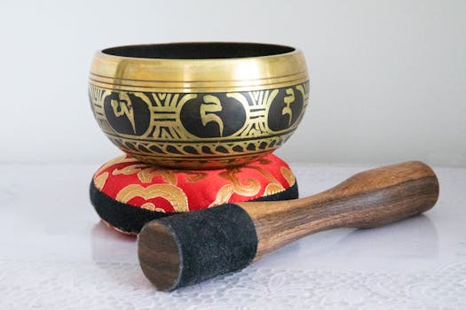 A close-up of a Tibetan singing bowl on a vibrant cushion, resting peacefully with a wooden mallet.
