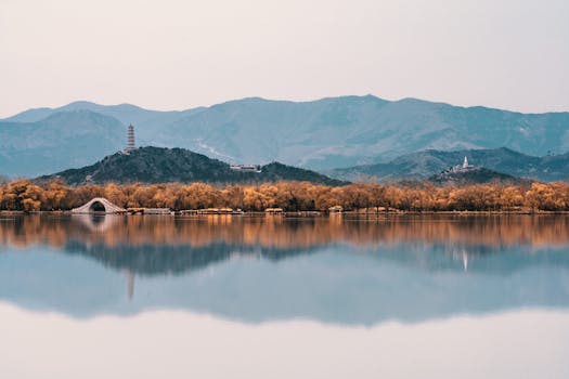 Tranquil autumn lake with mountain reflection and pagoda, showcasing serene landscape.