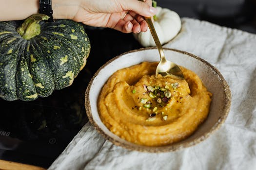 Close-up of a creamy pumpkin soup with pistachio garnish, perfect for autumn meals.
