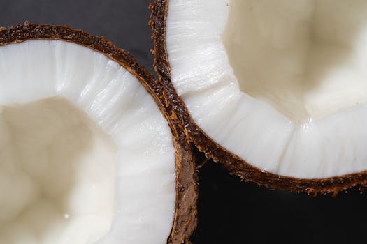 Detailed close-up of fresh coconut halves showing white kernel and rough shell.