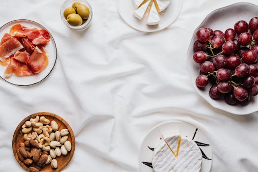 Top view of an elegant charcuterie spread with cheese, prosciutto, nuts, olives, and grapes.