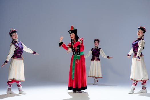 Four women in traditional Asian costumes performing a cultural dance indoors with vibrant movements and colorful dresses.