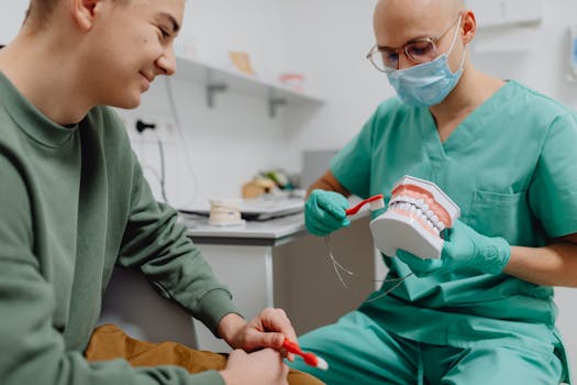A dentist demonstrates proper dental hygiene to a patient using a model.