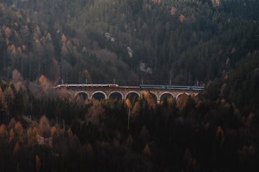 A scenic train travels across the historic Semmering Viaduct amidst the autumn forest in Austria.
