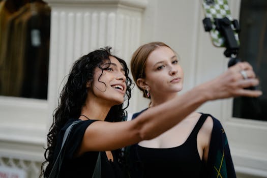 Two young women using a selfie stick to take a photo on a busy urban street, capturing a candid moment together.