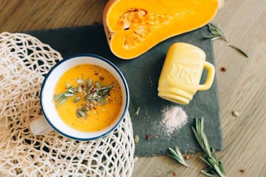 Top view of a creamy pumpkin soup garnished with seeds and rosemary, reflecting autumn flavors.