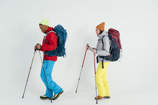 Two hikers in colorful winter gear with <a href='https://amzn.to/484WSwB' target='_blank'></img>trekking poles</a>, ready for an indoor photo shoot.