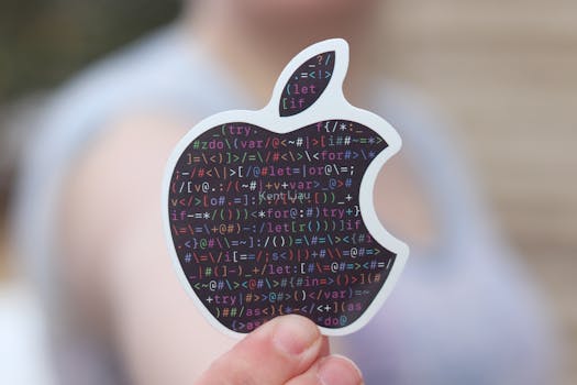 Close-up of a person holding an apple-shaped sticker with binary code, symbolizing technology.